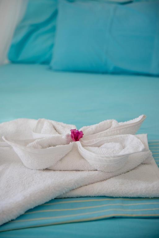 a bed with white towels and a pink flower on it at Paroscarmel studio-apartment in Logaras