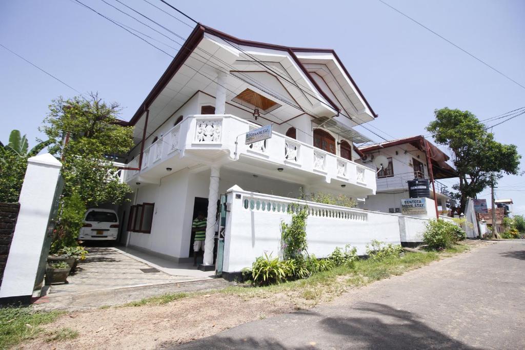 Uma casa branca com uma cerca branca à frente. em Bentota Home Stay em Bentota