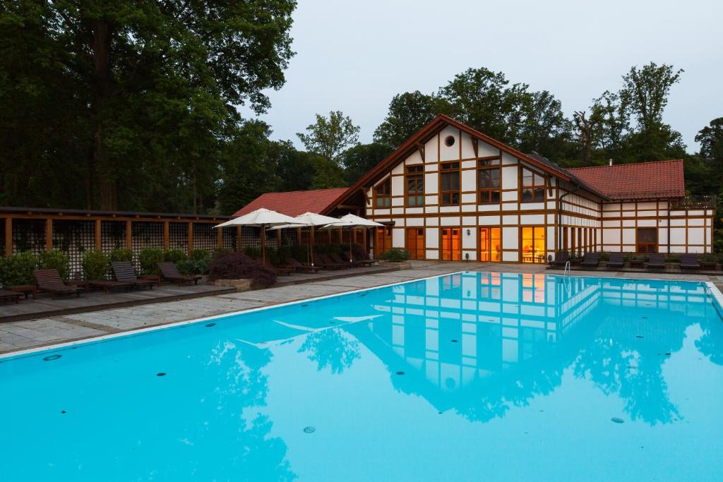 een groot huis met een zwembad ervoor bij Hotel Gut Klostermühle natur resort & medical spa in Alt Madlitz