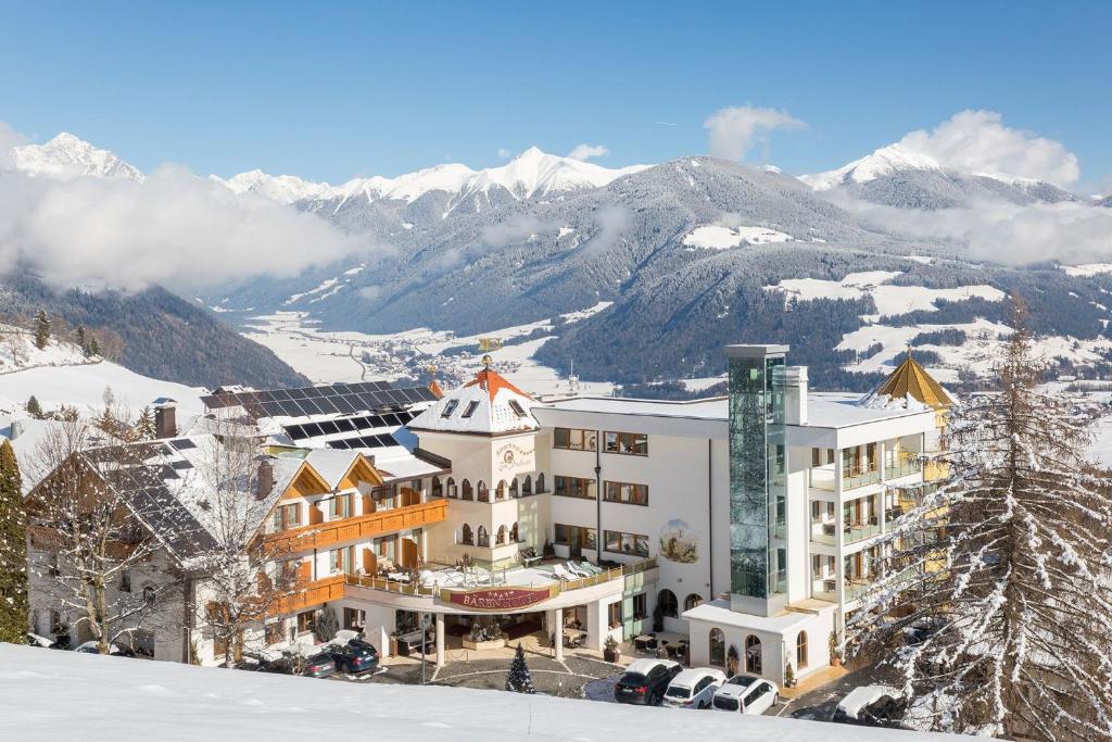 a hotel in the snow with mountains in the background at Bärenhotel in Valdaora
