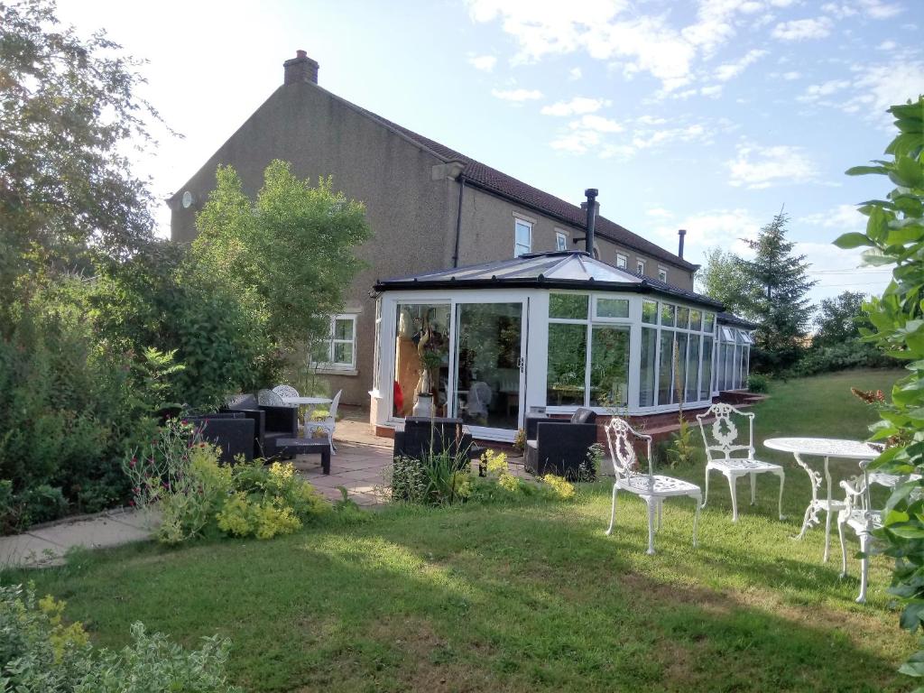 a house with a conservatory and chairs in the yard at Elmfield House in Bedale