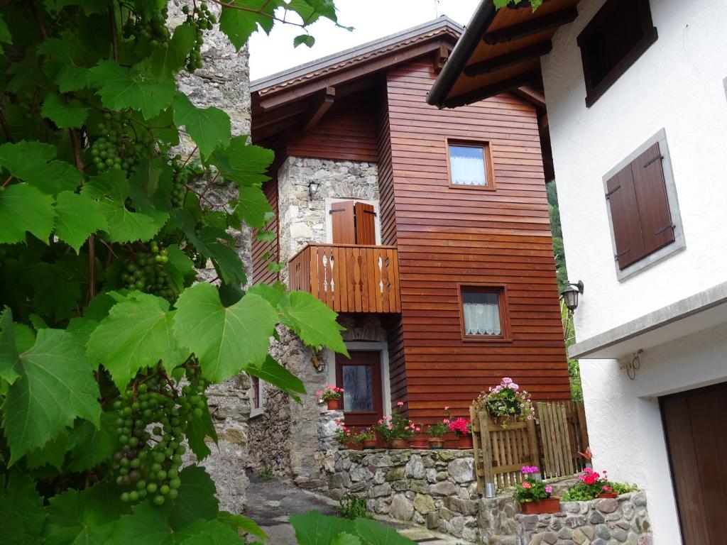 a wooden house with a balcony and flowers at Stalut das puestines in Arta Terme