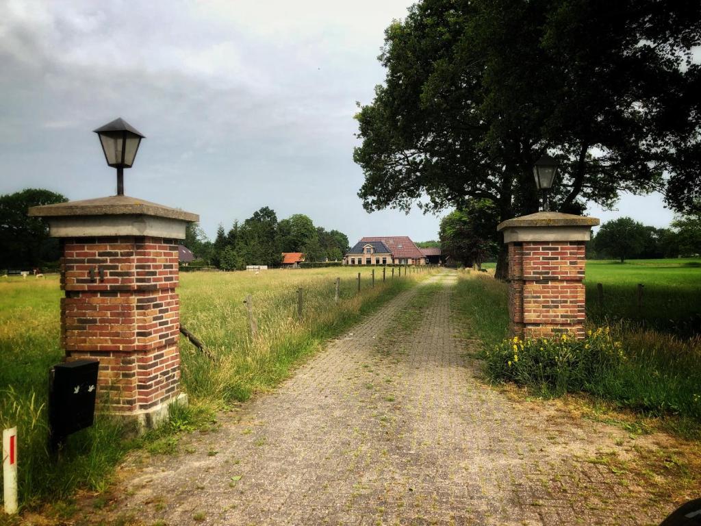 a dirt road with two brick pillars and a house at B&B Zandhuizen in Zandhuizen