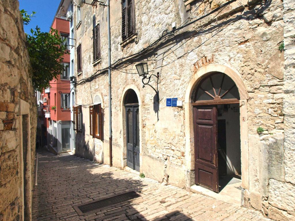 un vicolo con un antico edificio in pietra con porta in legno di Apartments Smaila 1729 a Pola (Pula)