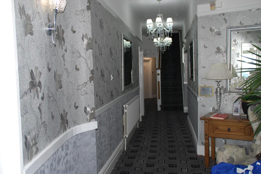 a hallway with a staircase with grey wallpaper at Brincliffe Hotel in Blackpool