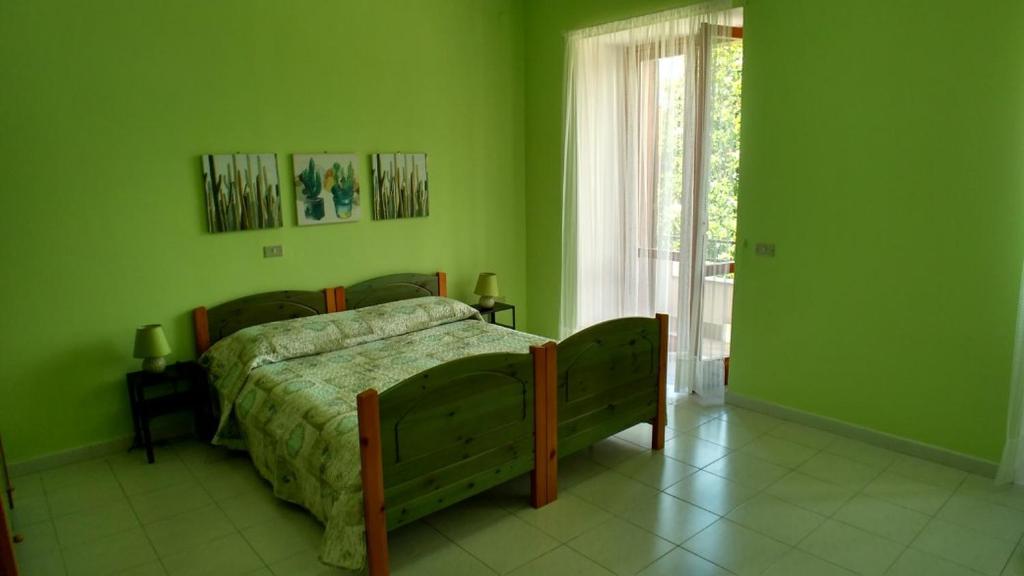 una camera da letto con un letto con pareti verdi e una finestra di La Magnolia sul Lago a Campolattaro