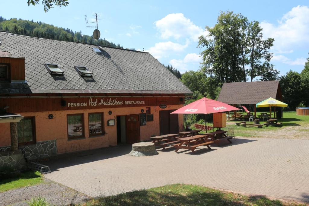 a building with a picnic table and a red umbrella at Pension Pod Hrádečkem in Höllenhäuser