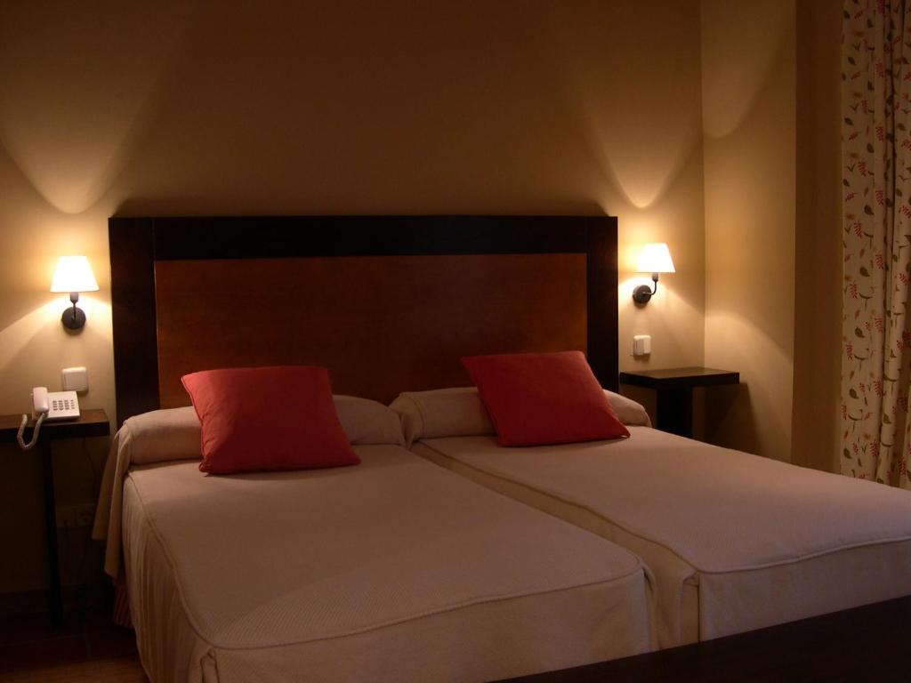 a bedroom with a large bed with two red pillows at Hotel Rural El Jardin de la Hilaria in Valsain