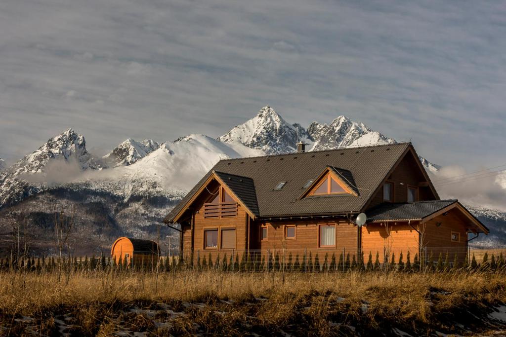 a wooden house in a field with mountains in the background at Pillow House Tatras in Stará Lesná