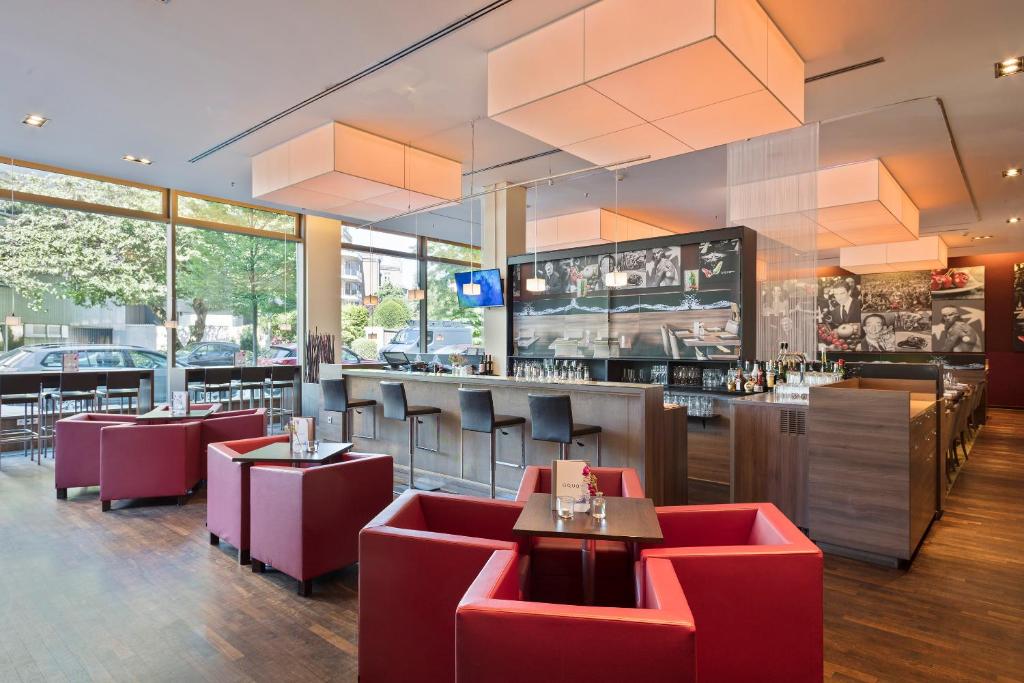 a restaurant with red chairs and a bar at Meliá Düsseldorf in Düsseldorf