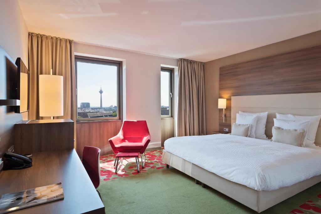 a hotel room with a bed and a red chair at Meliá Düsseldorf in Düsseldorf