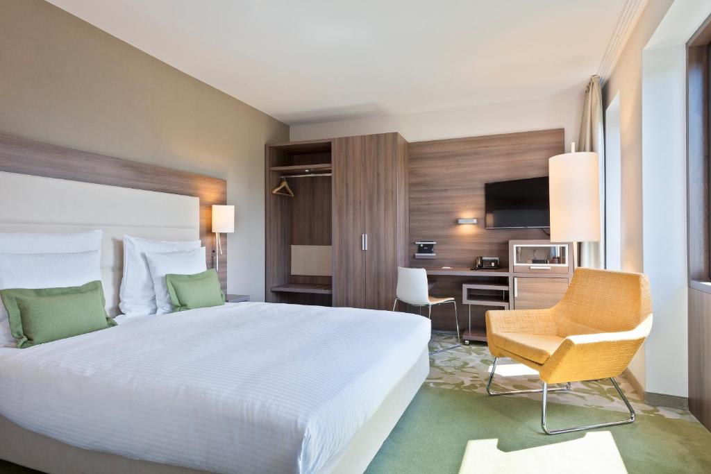 a bedroom with a large white bed and a desk at Meliá Düsseldorf in Düsseldorf