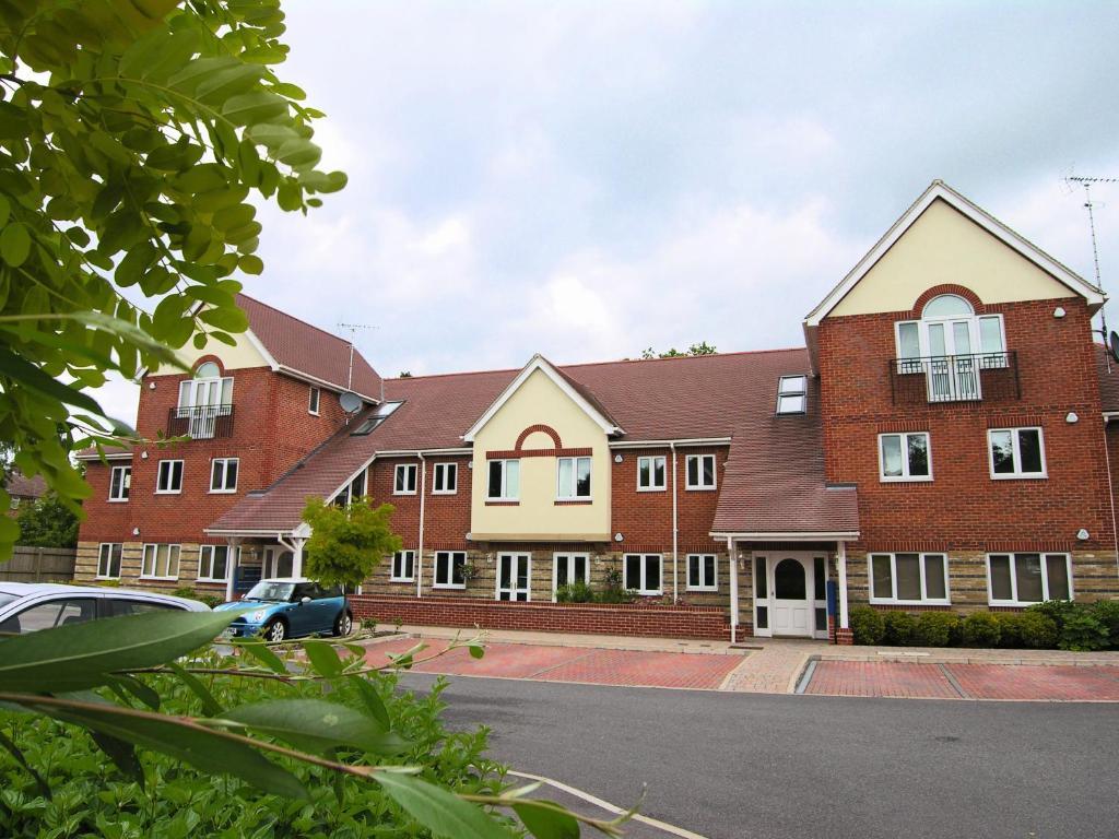 un grand bâtiment en briques avec une voiture garée devant dans l'établissement Berkshire Rooms Ltd - Gray Place, à Bracknell