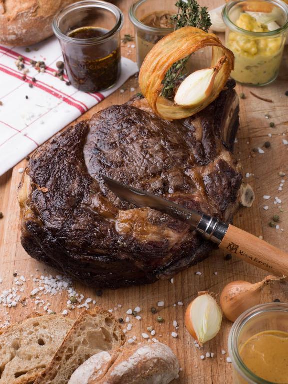 a steak on a cutting board with a knife and bread at Hôtel Alpen Ruitor in Méribel