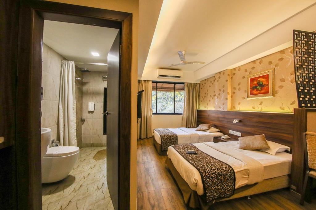 a hotel room with two beds and a bathroom at Hotel Maharana Inn Chembur in Mumbai