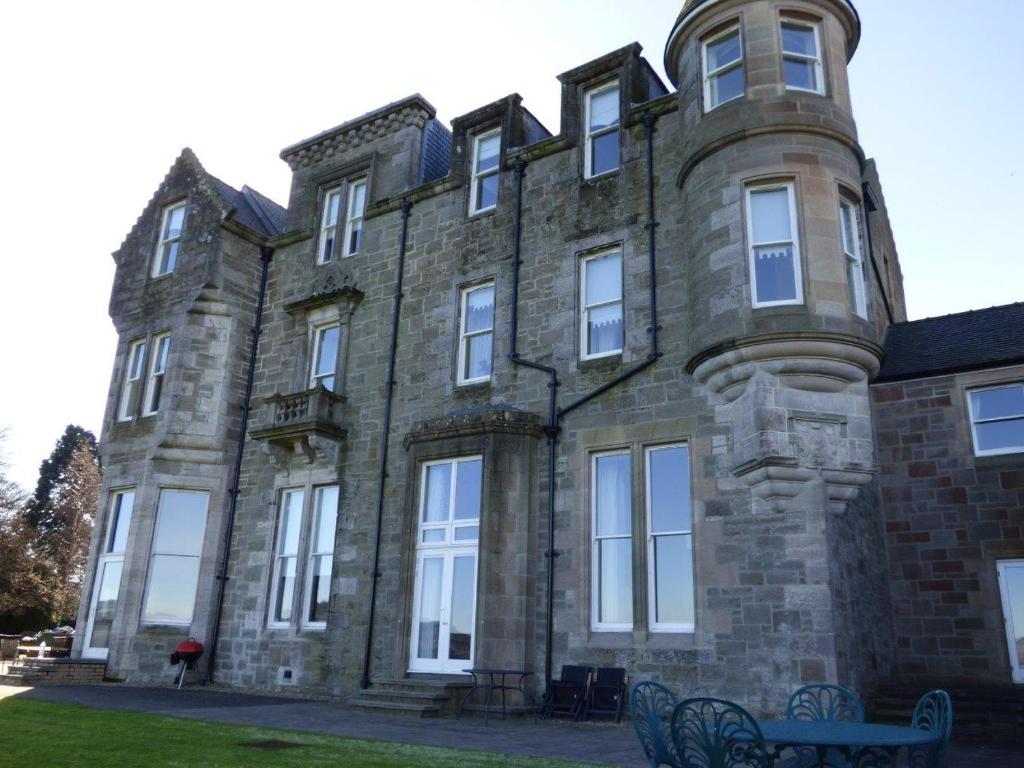 a large brick building with benches in front of it at The Pipers No 7 Lomond Castle in Balloch