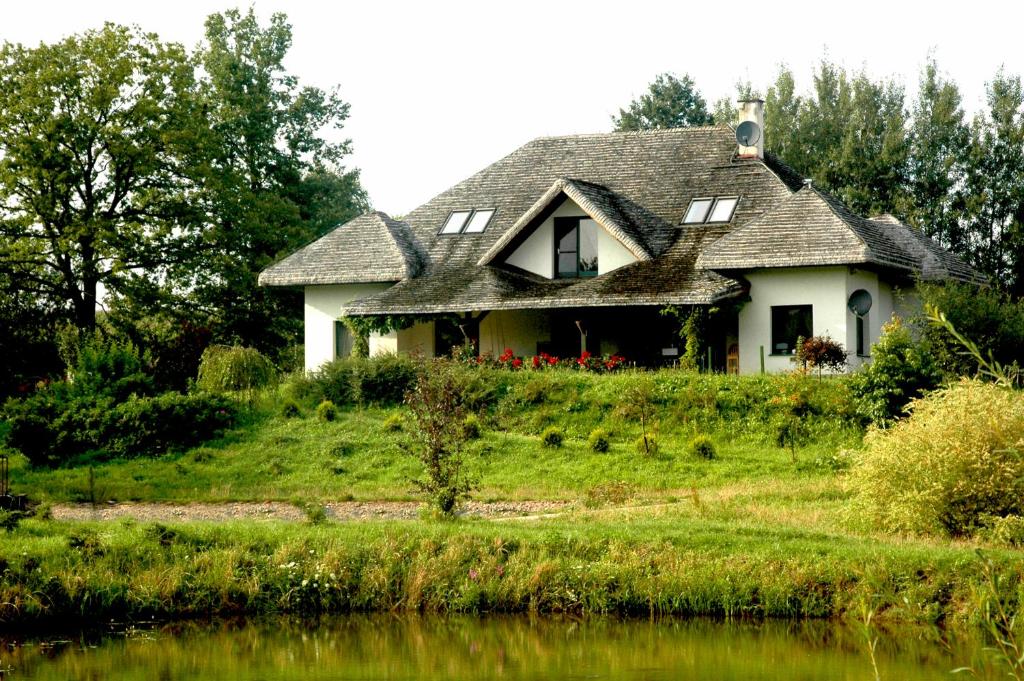 a house on a hill next to a body of water at Wodne Ogrody in Dobczyce