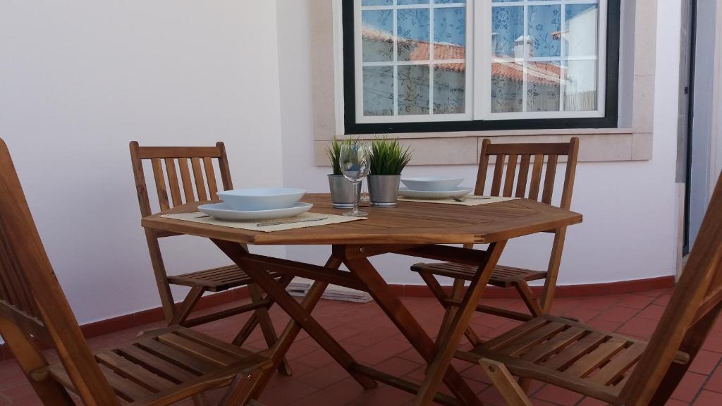 uma mesa de madeira com duas cadeiras e uma mesa com pratos em Apartamento Estúdio Pinhalmar em Vila Nova de Milfontes