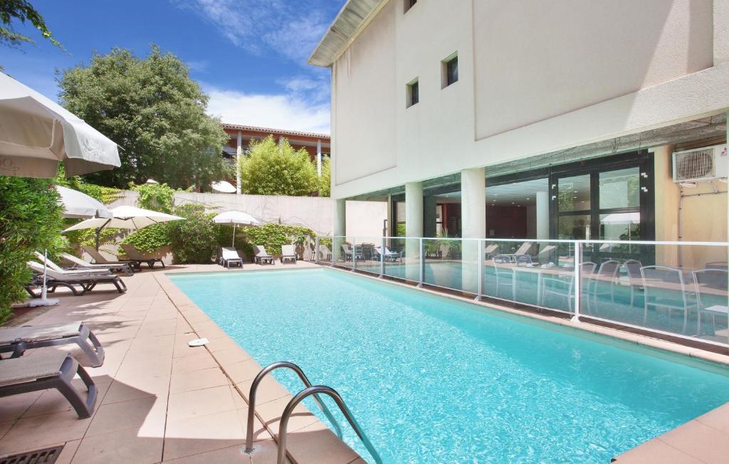 une piscine en face d'un bâtiment dans l'établissement Odalys City Aix en Provence Les Floridianes, à Aix-en-Provence