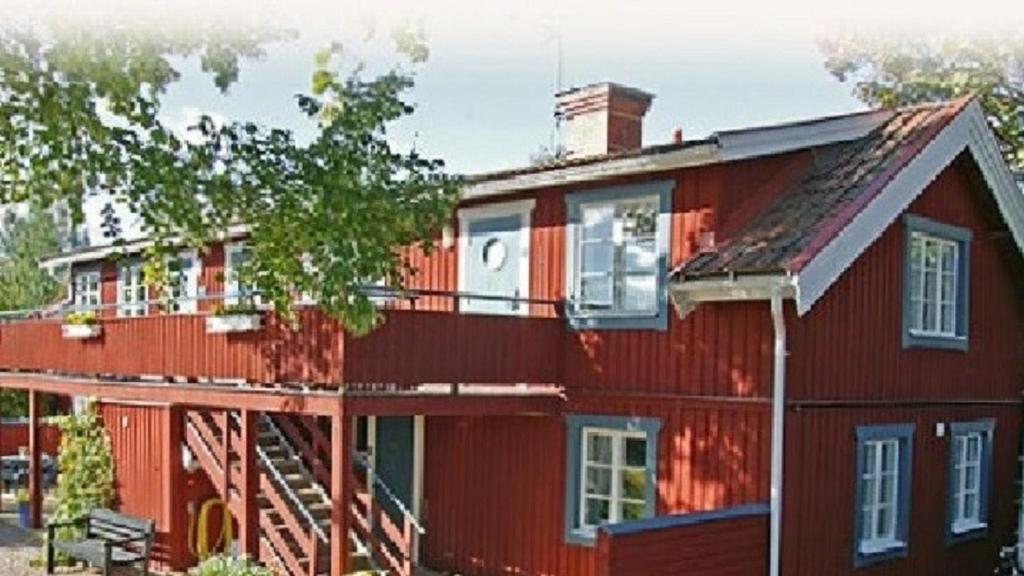 una casa roja con una terraza a un lado. en Classic Leksand, en Leksand