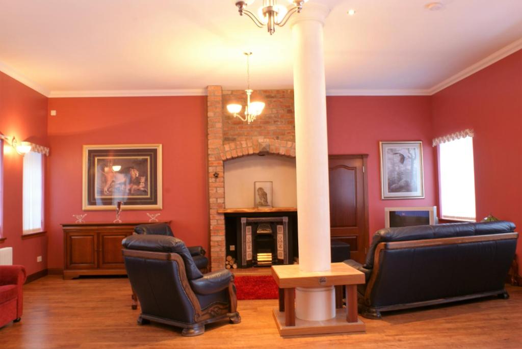 a living room with a pillar and chairs and a fireplace at Coachouse in Balloch