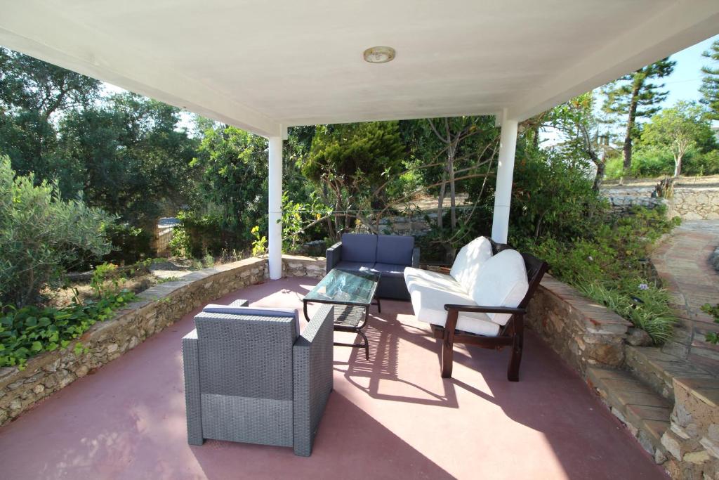 a porch with white chairs and a table and a table at Casa do Milho in Carvoeiro