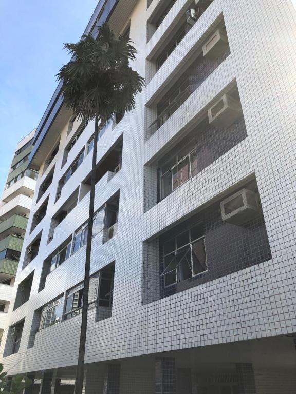 a tall white building with a palm tree in front of it at Apto próximo ao Shopping Iguatemi e Centro de Eventos in Fortaleza