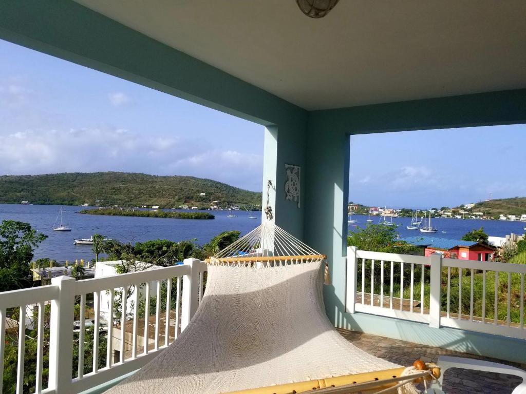 クレブラにあるIsland Charm Culebra Studios & Suites - Amazing Water views from all 3 apartments located in Culebra Puerto Rico!のハンモック付きのバルコニーから水辺の景色を望めます。