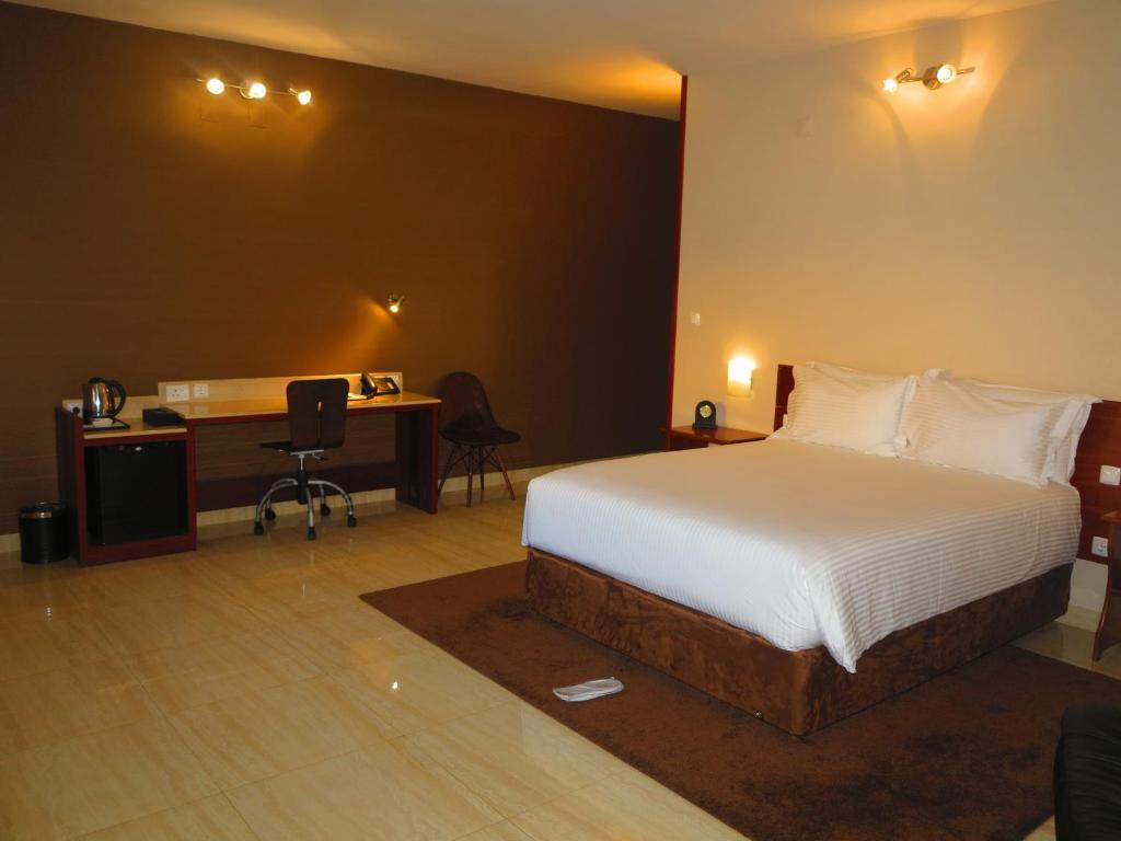 a bedroom with a bed and a desk with a computer at Hotel Castelo Branco in Chimoio