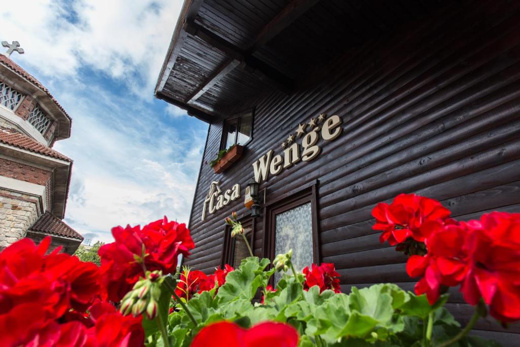 un groupe de fleurs rouges devant un bâtiment dans l'établissement Pension Casa Wenge, à Sinaia