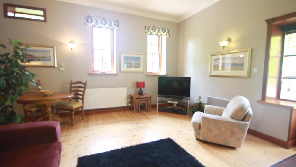 sala de estar con TV, mesa y sillas en Stables Lodge en Balloch