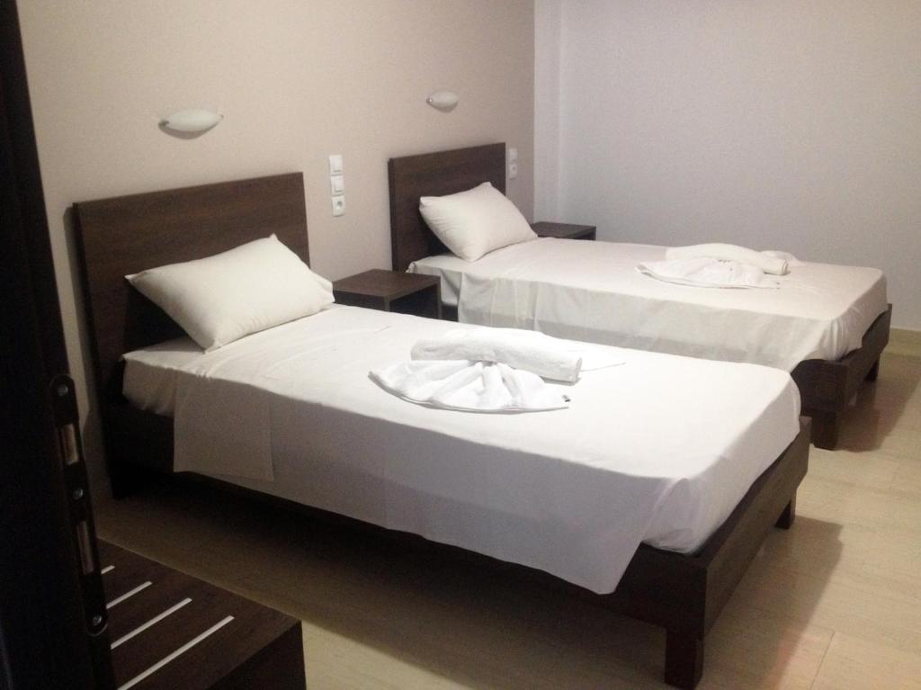 two beds in a hotel room with white sheets at Hotel Thisvi in Stalís