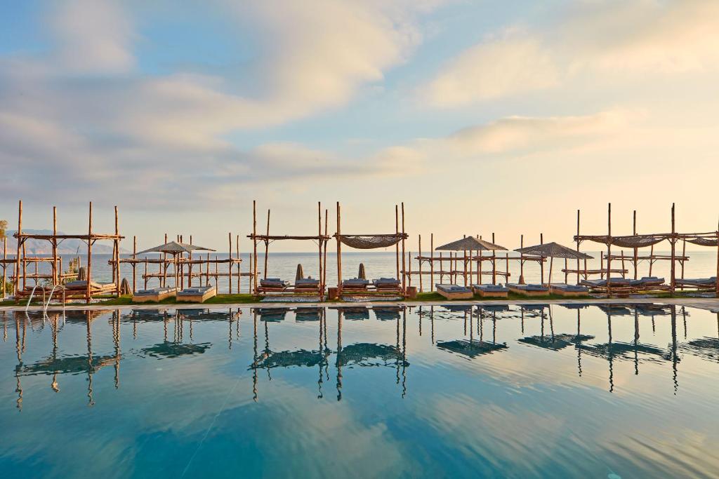 a large pool of water with tables and umbrellas at La Mer Resort & Spa - Adults Only in Georgioupolis