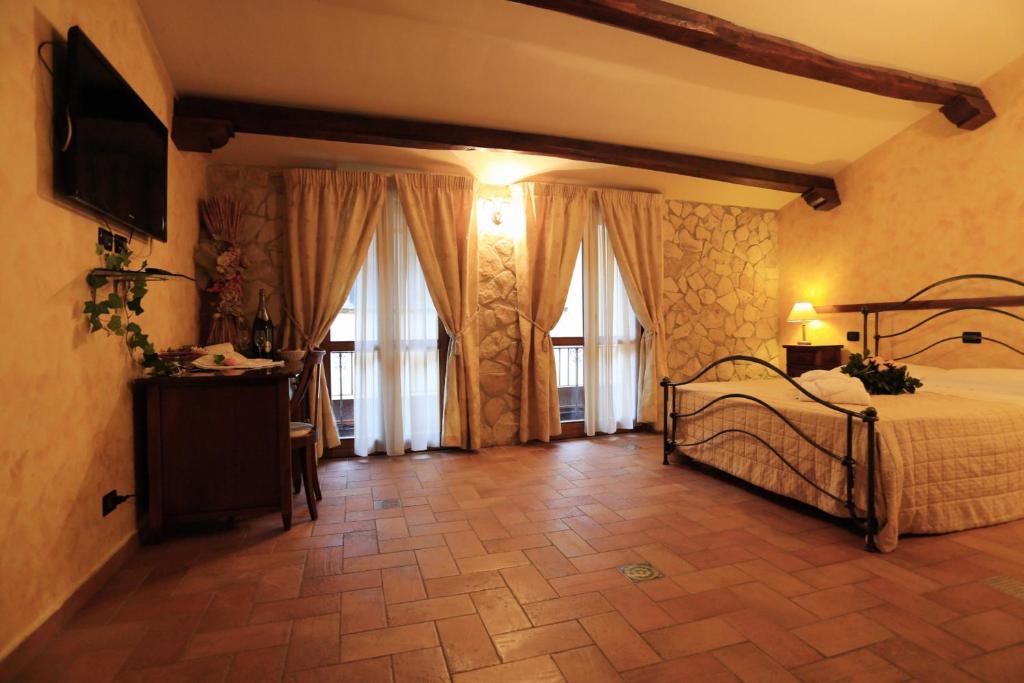 una camera da letto con un letto, una TV e finestre di Hotel L'Aquila a L'Aquila