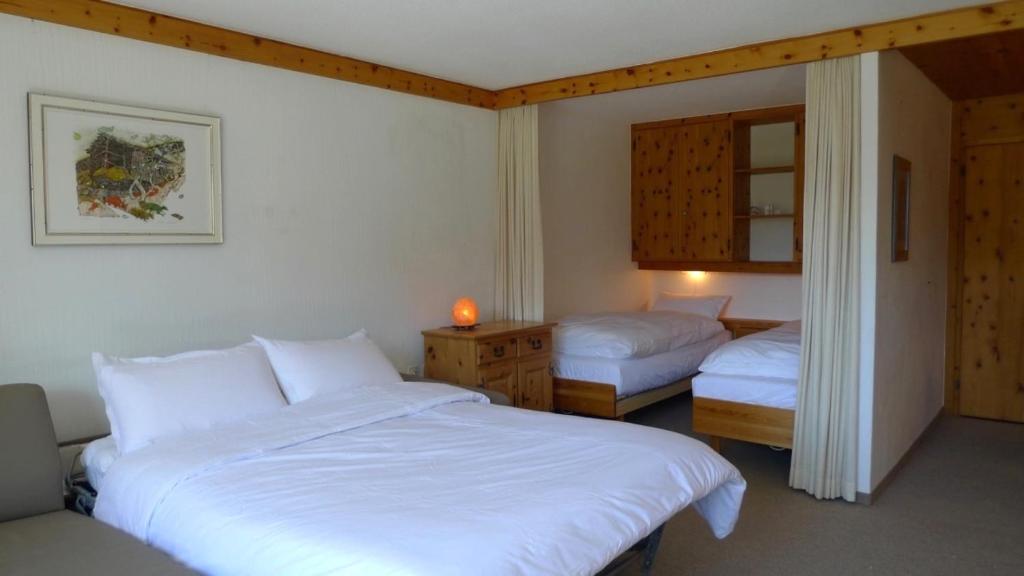 1 dormitorio con 2 camas con sábanas blancas y espejo en Spectacular View & Central Location in Davos, en Davos