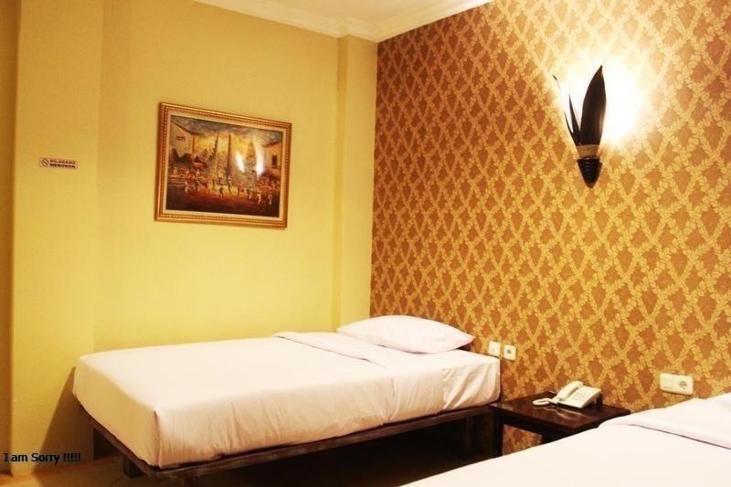 a bedroom with two beds and a picture on the wall at Twins Hotel in Jakarta