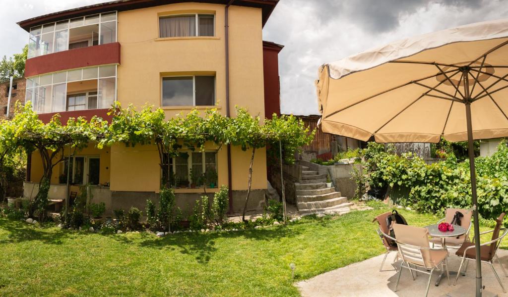 ein Haus mit einem Tisch und einem Sonnenschirm im Hof in der Unterkunft Апартаменти за гости Бошнакови in Dewin