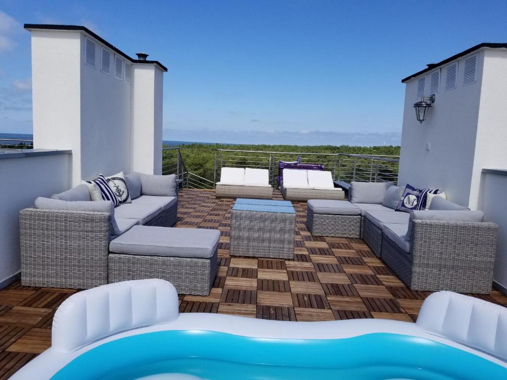 d'une terrasse avec canapés et d'un balcon avec piscine. dans l'établissement Apartamenty Marynarskie, à Rowy