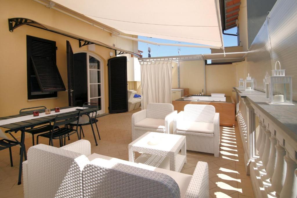 d'une terrasse avec des chaises blanches, une table et un comptoir. dans l'établissement Bonnes Vacances a Pietrasanta, à Pietrasanta