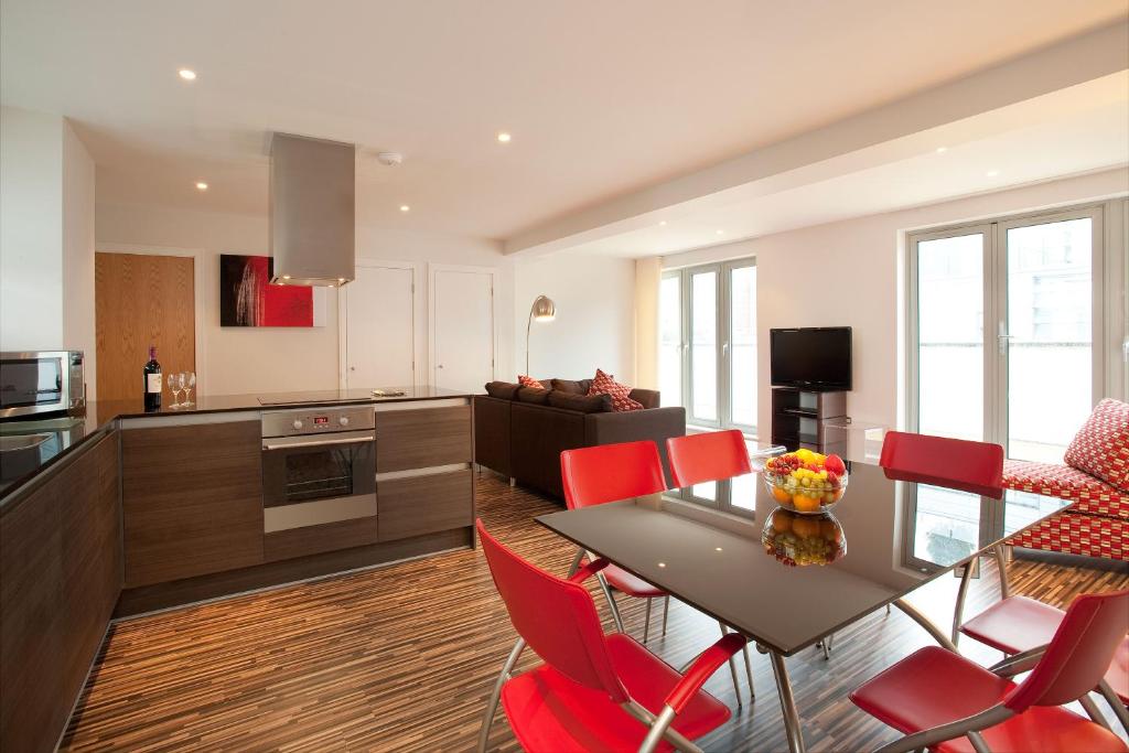 a kitchen and living room with a table and red chairs at SACO Holborn – Lamb’s Conduit St in London