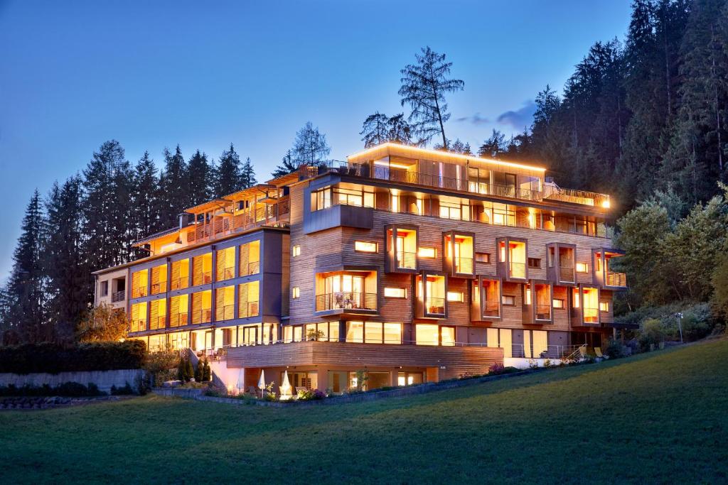 a large building on a hill at night at Naturhotel Die Waldruhe in Chienes