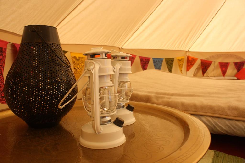 a table with two bottles and a vase on top of it at The Valley Bell Tents, Bring Your Own Bedding in Amroth