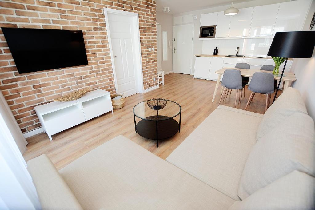 a living room with a white couch and a brick wall at Blue Park Apartament Bliżej Morza Kasprowicza in Kołobrzeg