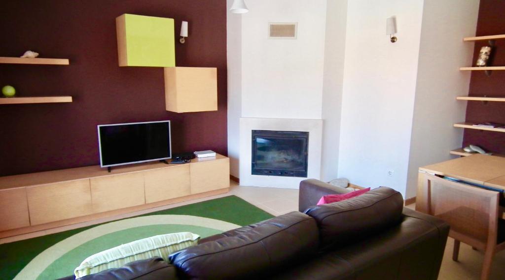 Apart. Dunas da Torreira في توريرا: غرفة معيشة مع أريكة ومدفأة