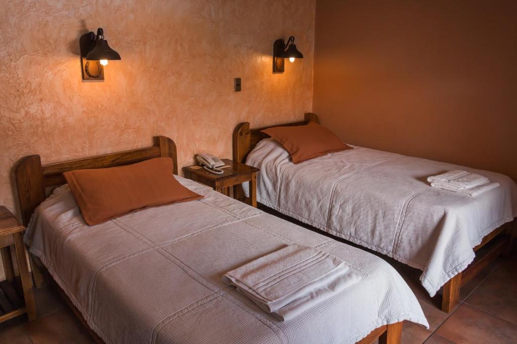 two beds in a hotel room with towels on them at La Escondida Hostal in Sucre