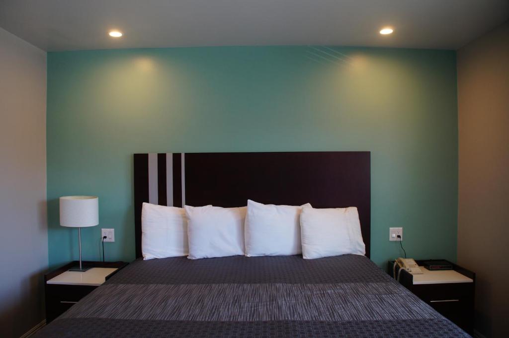1 dormitorio con 1 cama grande con almohadas blancas en Beach Inn Motel, en Long Beach