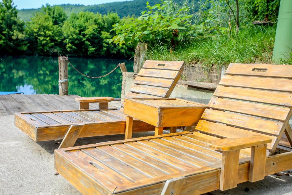 dos sillas de madera sentadas junto a un cuerpo de agua en Apartments River Una 3, en Bihać