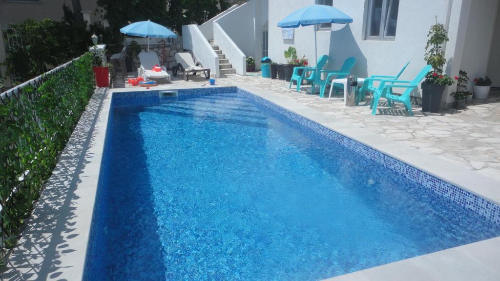 niebieski basen z niebieskimi leżakami i parasolami w obiekcie Brankas Apartments w Barze