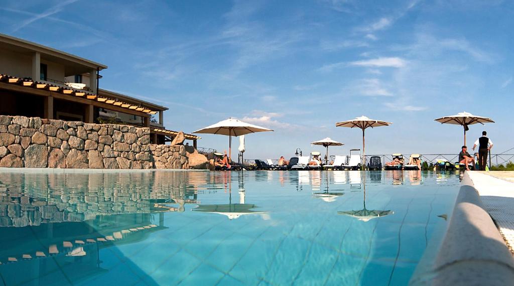 a pool with chairs and umbrellas in it at Hotel Villa Gustui Maris in Cala Gonone