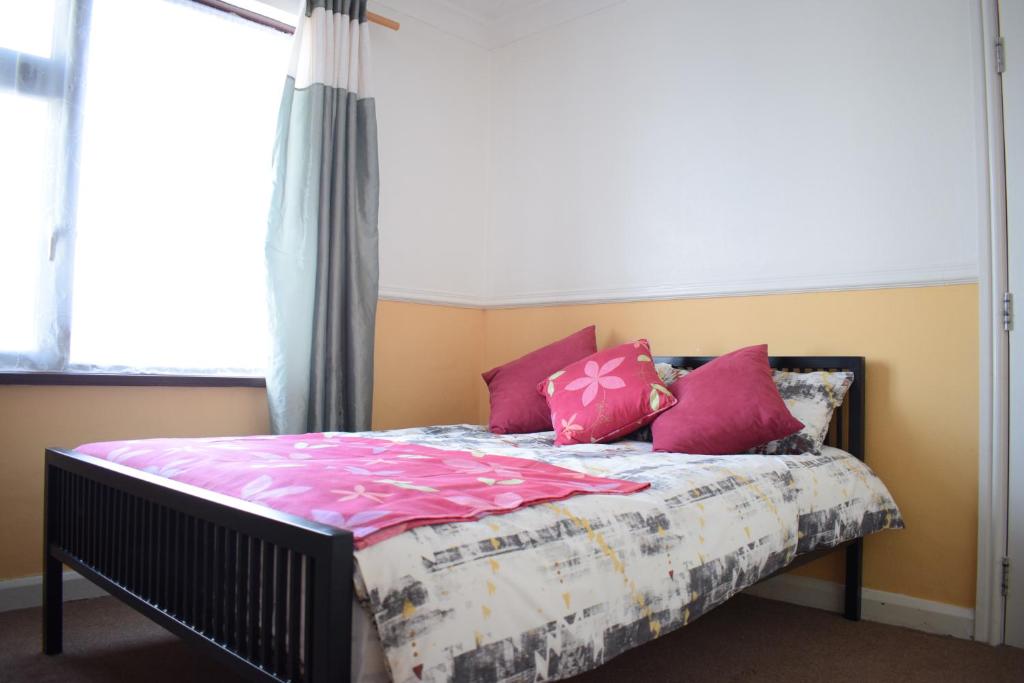 um quarto com uma cama com almofadas cor-de-rosa e uma janela em House Stay in Bangor North Wales em Bangor